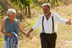 an older couple walking down a dirt road holding hands