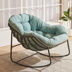 a chair sitting on top of a rug next to a plant in a living room