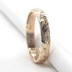 a gold wedding ring with an engraved design on the inside and outside, sitting on top of a white napkin