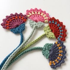 four crocheted flowers on a white surface