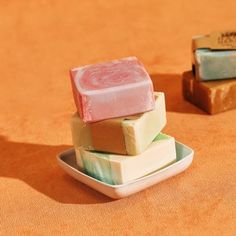 three soap bars stacked on top of each other in small dishes, one pink and one green