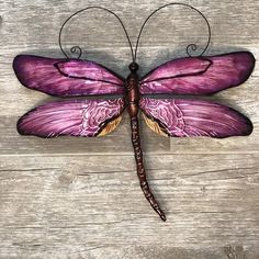 a purple dragonfly sitting on top of a wooden table