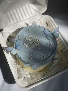 a blue cake with butterflies on it in a box