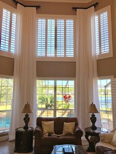 a living room filled with furniture and windows covered in white draping next to a pool