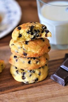 a stack of cookies sitting on top of a wooden cutting board next to a glass of milk