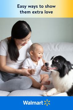 a woman sitting on top of a couch next to a baby and a black and white dog