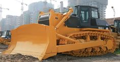 a large yellow bulldozer sitting on top of a dirt field