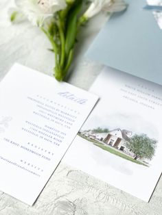 the wedding stationery is laid out on the table with white flowers and blue envelopes