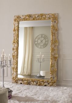 a large mirror sitting on top of a white rug next to a table with candles