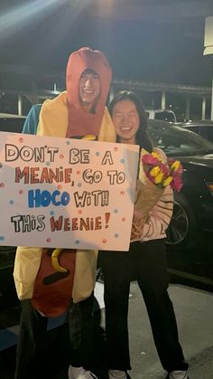 two people dressed as hotdogs holding a sign