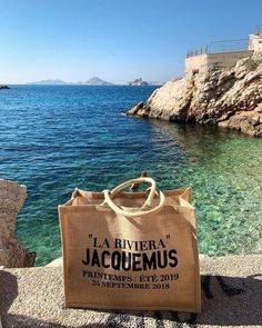 a jute bag sitting on top of a stone wall near the water's edge