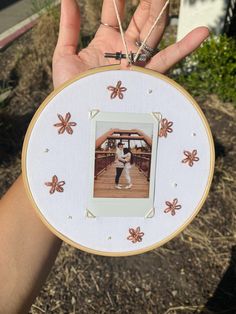 a person holding up an embroidered picture frame