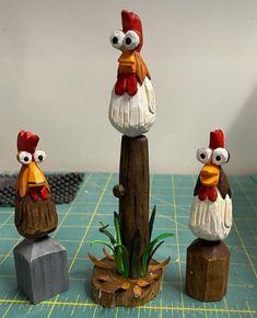 three chicken figurines sitting on top of a piece of wood next to each other