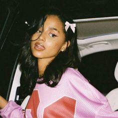 a young woman sitting in the back seat of a car wearing a pink shirt and bow tie