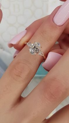 a woman's hand with pink manicured nails and a diamond ring