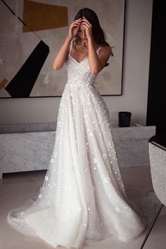 a woman standing in front of a painting wearing a wedding dress with sequins