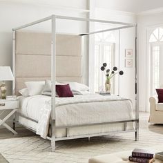 a bedroom with a four poster bed and white walls, carpeted flooring and furniture