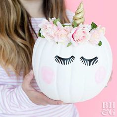 a girl holding a white pumpkin decorated with flowers and eyelashes