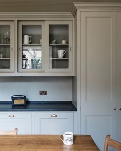 a kitchen with white cabinets and blue counter tops, along with a wooden dining room table