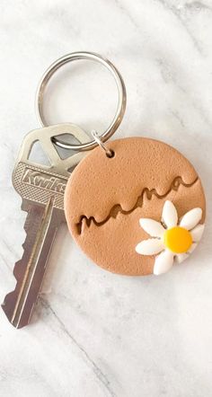 a keychain with a flower on it sitting next to a pair of keys