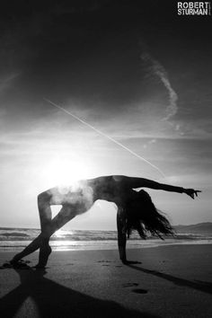 a woman standing on one leg in the sand