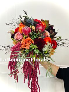 a woman holding a bouquet of flowers in her hand with the words la boutique florals