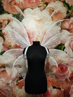 a mannequin with white wings and flowers behind it on a black display stand