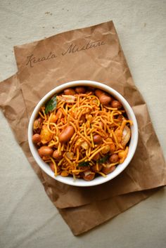 a white bowl filled with pasta and beans on top of a piece of brown paper