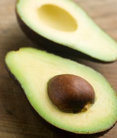 an avocado cut in half on a wooden table