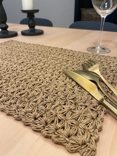 a place mat with two forks and a wine glass on the table next to it