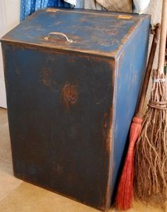 an old blue box sitting on the floor next to brooms