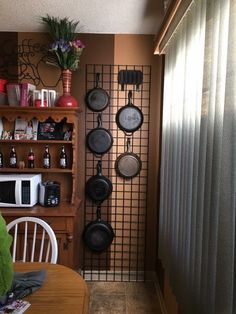 pots and pans are hanging on the wall next to a table with two chairs