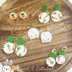 the carrots and corn earrings are on display in front of a wooden plate with bunny ears