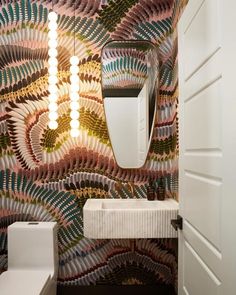 a bathroom with a sink, mirror and lights on the wall next to a toilet