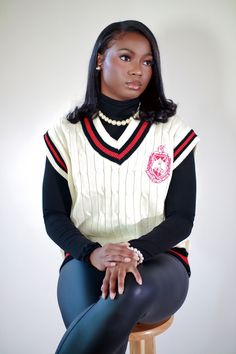 a woman sitting on top of a wooden stool wearing a sweater and leggings