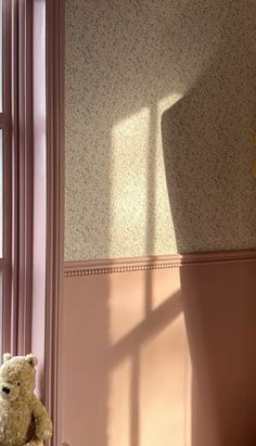 a teddy bear is sitting in the corner of a room with pink walls and floral wallpaper