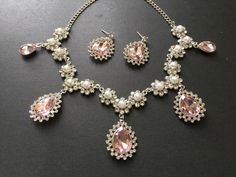 ** This listing comes with a necklace together with a pair of matching studs at back design earrings. ** Romantic design jewellery set featuring white faux pearls and clear/pink rhinestones crystals on top. We have also added an extra long cable chain at end for you to adjust the length. Just elegant and romantic! Size: necklace measures around 17" long x center drop 2.1".  Earrings around 1.25" drop x 0.9" width Color: silver plated with clear/pink rhinestones crystals and faux pearls  ** Pleas Pink Crystal Jewelry Sets For Wedding, Pink Bridal Necklace With Matching Earrings For Wedding, Pink Rhinestone Wedding Jewelry, Pink Dangle Necklaces For Wedding, Elegant Pink Rhinestone Jewelry Set, Pink Wedding Necklaces With Matching Earrings, Pink Necklaces With Matching Earrings For Wedding, Elegant Pink Bridal Necklace With Jewels, Pink Teardrop Pendant Jewelry For Wedding