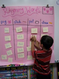 a young boy writing on a pink bulletin board with post - it notes attached to it