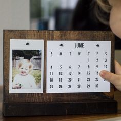 a wooden frame with two photos attached to it, and a calendar on the front