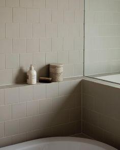 a white bath tub sitting next to a bathroom sink with a mirror on the wall