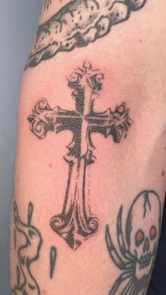 a cross and skull tattoo on the arm