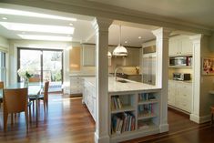 an open kitchen and dining room with wood flooring, white cabinets and counter tops