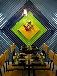 a dining room with green, yellow and blue wall art above the table set for four