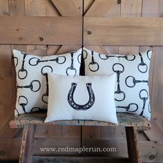 two pillows on a bench in front of a barn door with horseshoes and hooks