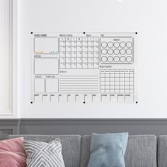 a living room with a couch, pillows and a wall mounted calendar on the wall