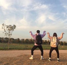 two people standing in the dirt with their arms up