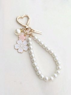 a keychain with pearls and a flower attached to it on a white surface