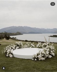 an outdoor ceremony setup with flowers and greenery on the grass, overlooking a body of water