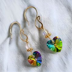 Illuminate your style with these beautiful crystal heart earrings, exuding sparkle and a vibrant array of rainbow colors. The handmade earring hooks, crafted with 10K gold-filled wire, add a touch of elegance. At the top, the gemstone bead is an aura Quartz paired with a gold-plated spacer bead, enhancing the overall charm. This listing offers one pair of these mesmerizing rainbow crystal heart earrings, with quantities available in the drop-down menu. Each earring measures between 20 - 25mm, in Tiny Heart Earrings, Crystal Heart Earrings, Gold Heart Earring, Winter Earrings, Handmade Earring, Rainbow Colours, Heart Dangle Earrings, Sparkly Earrings, Rainbow Crystal