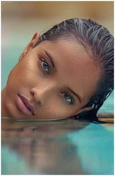 a woman laying on top of a swimming pool with her head above the water's surface